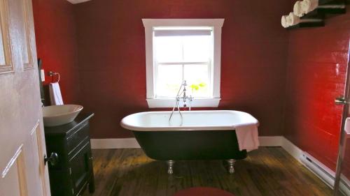 a red bathroom with a bath tub and a window at The Old Salt Box Co. - Mary's Place in Fogo
