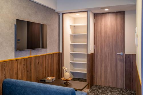 a living room with a blue couch and a tv at Apartment Hotel 11 Higashi Umeda in Osaka