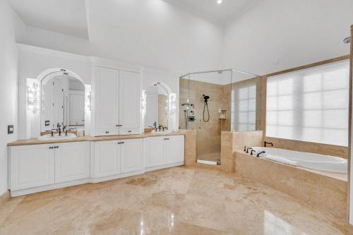 ein Badezimmer mit zwei Waschbecken, einer Badewanne und einer Dusche in der Unterkunft Waterfront Luxury Villa Heated Pool with Afternoon Sun Coral Key in Fort Lauderdale