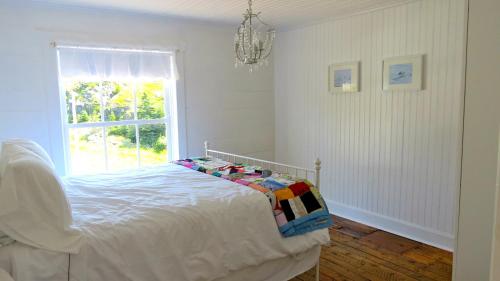 ein weißes Schlafzimmer mit einem Bett und einem Fenster in der Unterkunft The Old Salt Box Co. - Evelyn's Place in Herring Neck