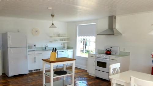 a kitchen with white cabinets and a white refrigerator at The Old Salt Box Co. - Evelyn's Place in Herring Neck