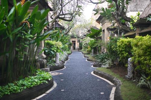 a walkway through a garden with plants and trees at Puri Dewa Bharata Hotel & Villas in Legian