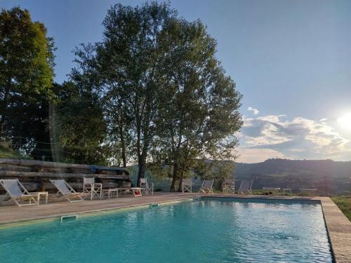 a swimming pool with chairs and trees and the sun at Tenuta Montanello B&B in Castiglione Falletto