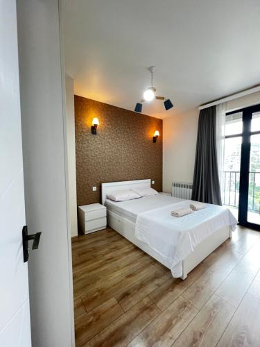 a bedroom with a white bed and a wooden floor at Comfort Stay Saburtalo in Tbilisi City