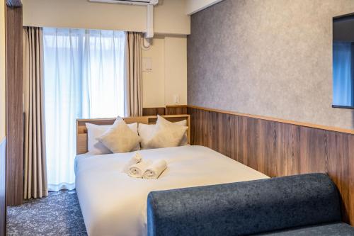 a hotel room with a bed with towels on it at Apartment Hotel 11 Higashi Umeda in Osaka