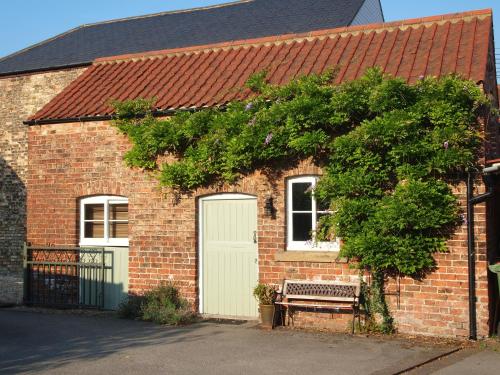 a brick house with a bench and a tree at The Stables at Owlett Hall in Crowle