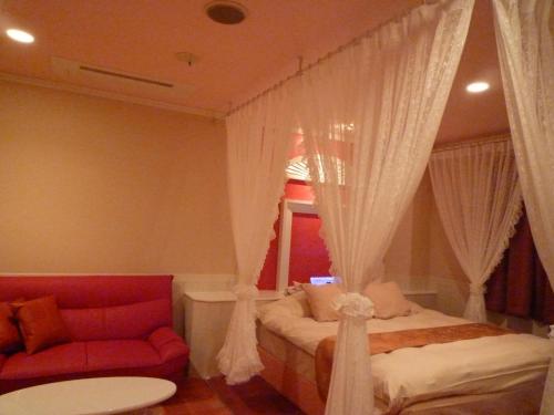 a bedroom with a bed with curtains and a couch at ホテルカホウ 千葉土気店 Chiba-Toke "大網市街から車で10分 茂原市街から車で15分" in Chiba