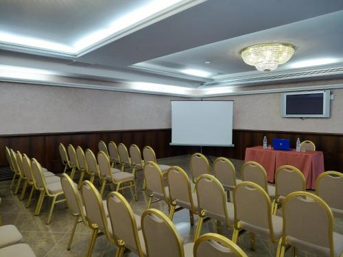 einen Konferenzraum mit einem Tisch, Stühlen und einem Bildschirm in der Unterkunft Hotel Lucrezia Borgia in Ferrara