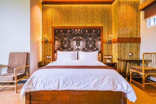 a bedroom with a large bed and two chairs at Horison Resort Dieng in Kejajar