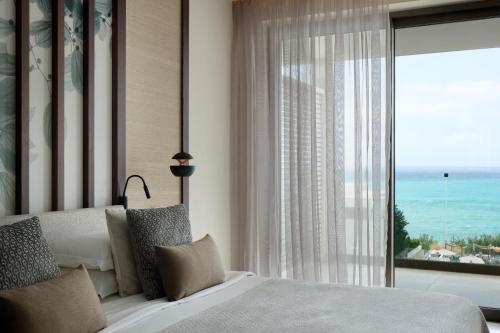 a bedroom with a bed and a large window at Mare Paphos in Paphos