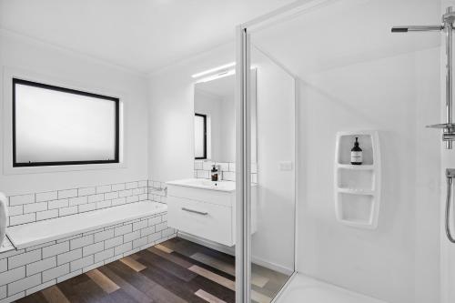 a white bathroom with a shower and a sink at Sunrise Hideaway - Cromwell Holiday Home in Cromwell
