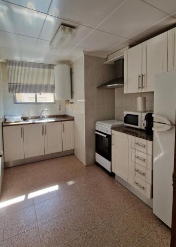 a kitchen with white cabinets and a white refrigerator at Apartamento CA VALEN 6 in Peniscola