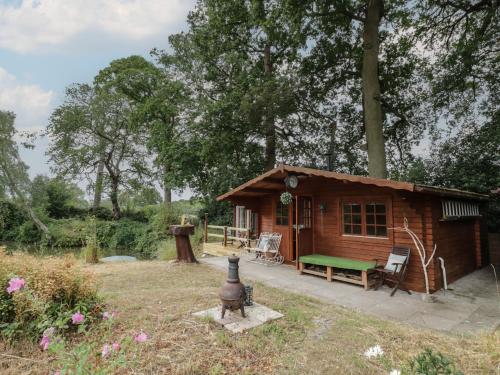 a small wooden cabin with a bench and a fire hydrant at Carps Well Lodge in Warwick