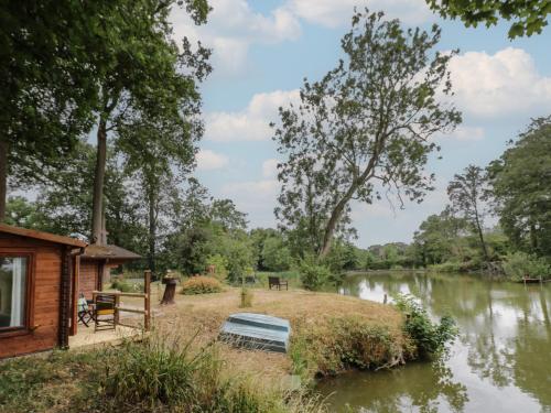 a cabin next to a river with a boat at Carps Well Lodge in Warwick