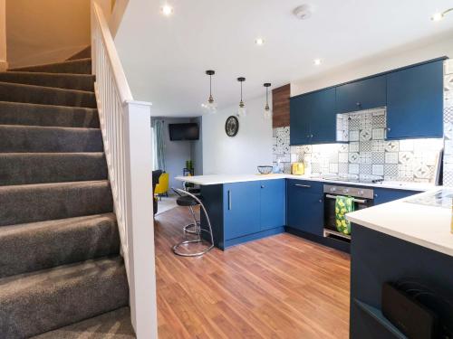 a kitchen with blue cabinets and a staircase at 8 Wharfedale Mews in Otley