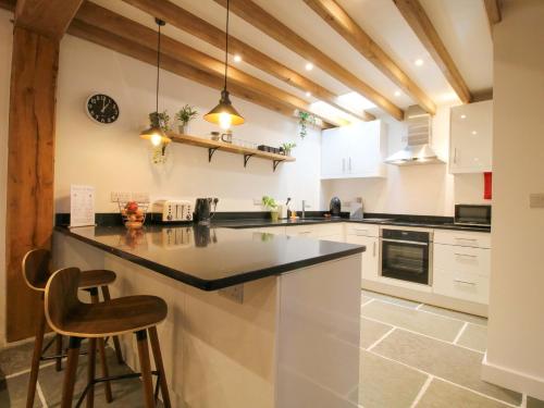 a kitchen with white cabinets and a black counter top at The Hideaway in Bishops Castle