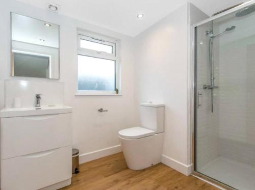 a white bathroom with a toilet and a shower at Sea Breeze in Poole