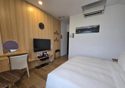 a hotel room with a bed and a television at Lukang Holiday Hostel in Lugang