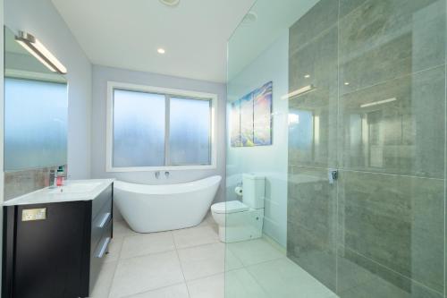 a bathroom with a tub and a toilet and a shower at Mountain View - Kaikoura Holiday Home in Kaikoura