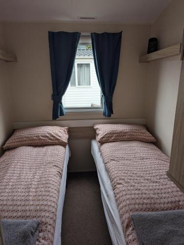 two beds in a small room with a window at Salsa static caravan close to Edinburgh in Port Seton