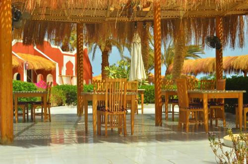 a restaurant with tables and chairs under a straw umbrella at Sun Beach Hotel ABO SOMA in Hurghada