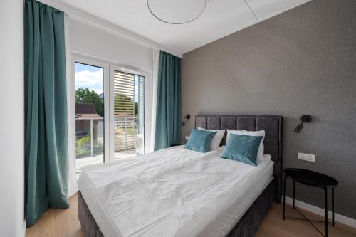 a bedroom with a bed with blue pillows and a window at ReVital Mechelinki by Homeprime Parking Free in Mechelinki