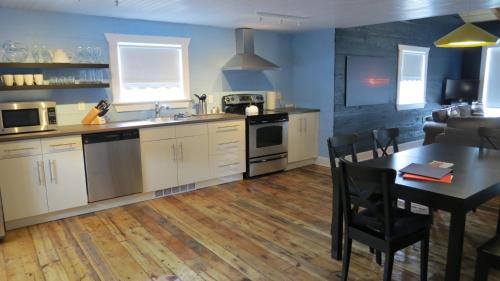 a kitchen with white cabinets and a table with a dining room at The Old Salt Box Co - Gertie's Place in Twillingate