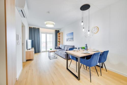 a dining room and living room with a table and blue chairs at ReVital Mechelinki by Homeprime Parking Free in Mechelinki