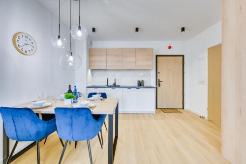 a kitchen and dining room with a table and blue chairs at ReVital Mechelinki by Homeprime Parking Free in Mechelinki