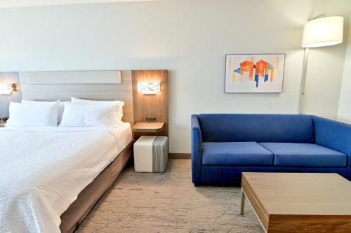 a hotel room with a bed and a blue couch at Holiday Inn Express & Suites Palm Coast - I-95 in Palm Coast