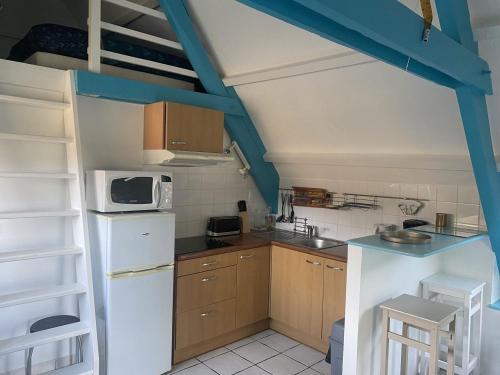 a small kitchen with a white refrigerator and a microwave at GITE Le BELLEVUE 2-4 pers, piscine, billiard et baby-foot in Sainte-Hélène