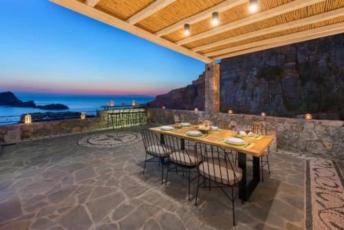 a patio with a table with chairs and a view of the ocean at Lindos Vigli Private Villa in Lindos