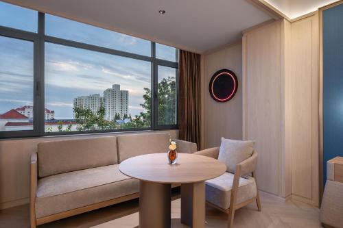 a living room with a couch and a table at Orange Crystal Qingdao May Fourth Square Olympic Sailing Center Hotel in Qingdao
