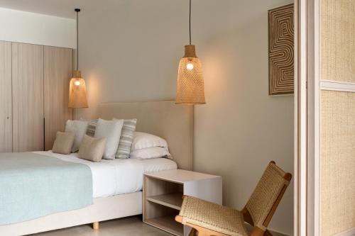 a bedroom with a bed and a chair and two lights at Mare Paphos in Paphos