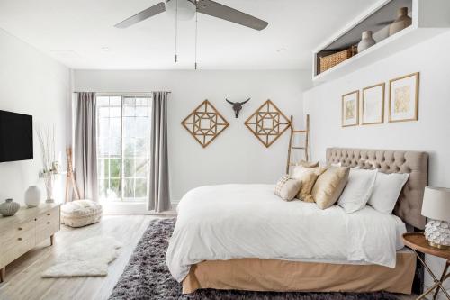 a white bedroom with a large bed and a tv at Silver Triangle Oasis with Verdant Backyard in Los Angeles