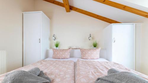 a bedroom with a bed with pink and gray pillows at Haus Seeblick mit 9 Wohnungen in Alt Reddevitz