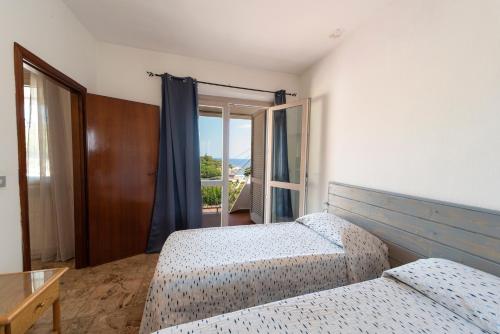 a bedroom with two beds and a large window at La casa di Grace in Seccheto