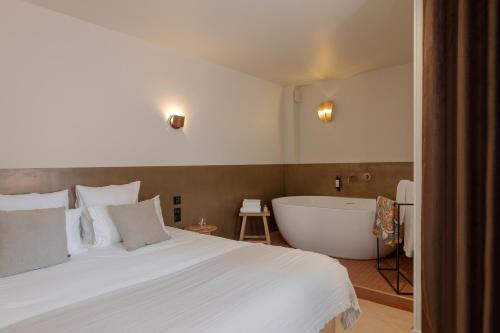 a bedroom with a large bed and a bath tub at MiHotel Le Gourguillon in Lyon