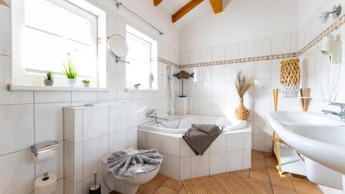 a bathroom with a tub and a sink and a toilet at Haus Seeblick mit 9 Wohnungen in Alt Reddevitz