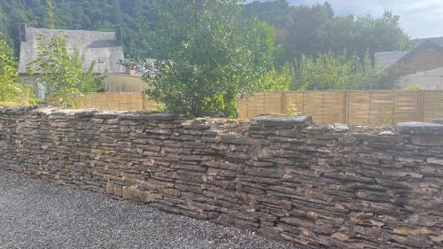 a stone retaining wall in front of a fence at The Refuge of Happiness in Bouillon