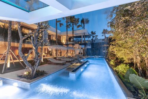 een zwembad met stoelen en bomen en een gebouw bij Villa Zeno Arete Pererenan 6 Bedroom , Ice Bath, Sauna and Gym in Tumbak Bayuh