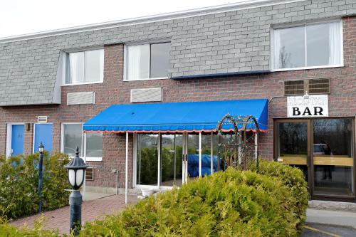 a bar with a blue awning in front of a building at Hotel Transit in Mont-Saint-Hilaire