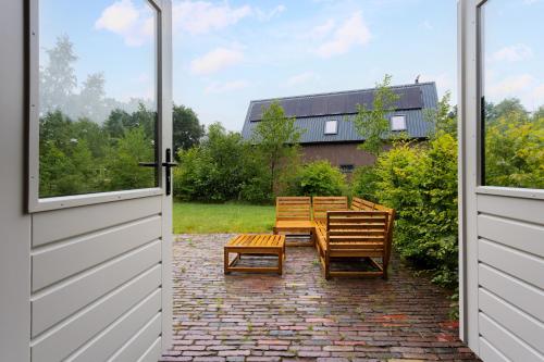 an open door to a patio with chairs and tables at Boshuisje Luna | 4 personen - Vakantiepark De Kremmer in Gasselte