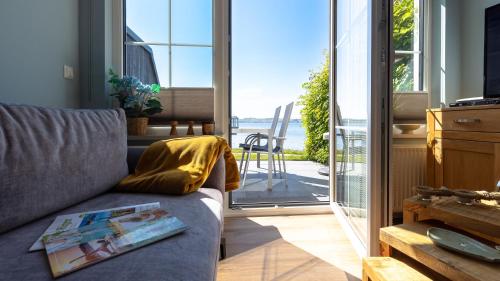 a living room with a couch and a sliding glass door at Haus Seeblick mit 9 Wohnungen in Alt Reddevitz