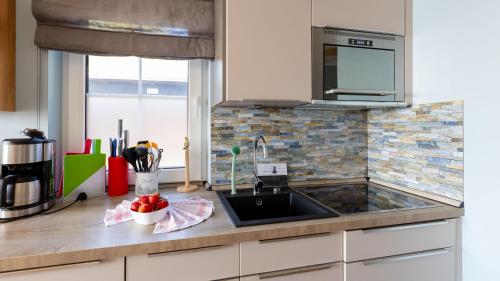 a kitchen counter with a sink and a microwave at Haus Seeblick mit 9 Wohnungen in Alt Reddevitz