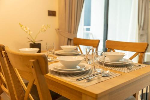 a wooden table with plates and bowls on it at C111 Modern 2BR Escape, Steps to Beach & Cafes in Nai Yang Beach