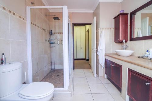 a bathroom with a toilet and a shower and a sink at North Hill Guesthouse in Bloemfontein