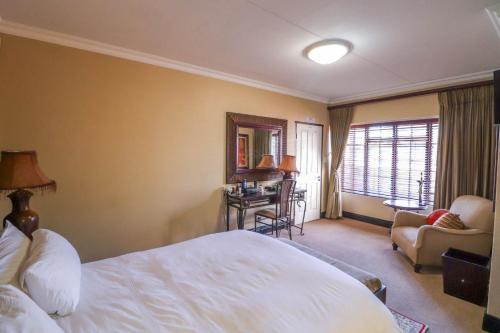 a hotel room with a white bed and a desk at North Hill Guesthouse in Bloemfontein