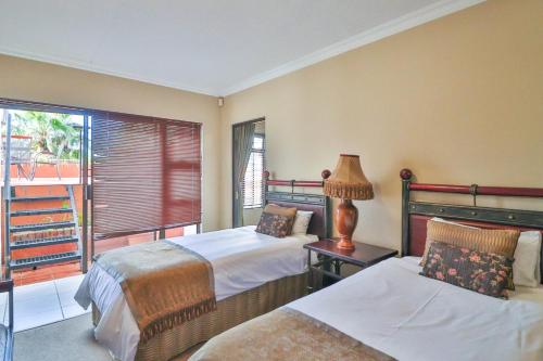 a hotel room with two beds and a window at North Hill Guesthouse in Bloemfontein
