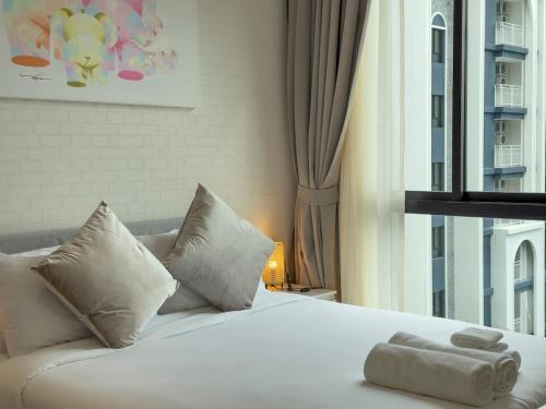a white bed with two pillows and a window at C111 Modern 2BR Escape, Steps to Beach & Cafes in Nai Yang Beach